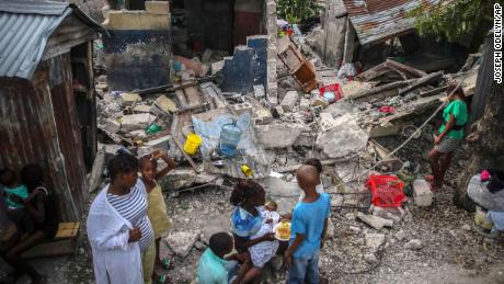 Une famille prend son petit-déjeuner devant des maisons détruites par un séisme de magnitude 7,2 aux Cayes, en Haïti, le dimanche 15 août.