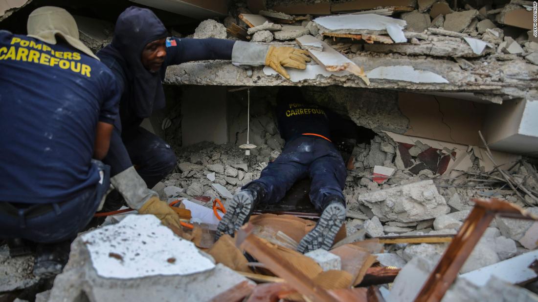 Firefighters search for survivors inside a collapsed building in Les Cayes on August 15.