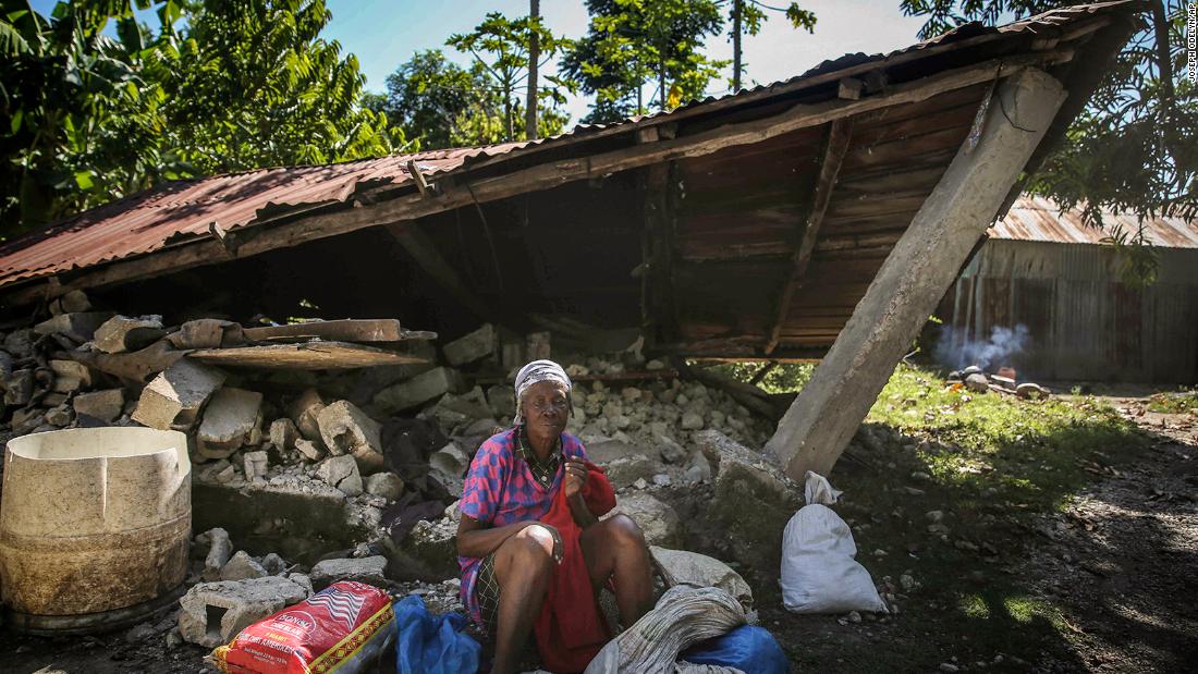 A woman sits in front of a destroyed house after the earthquake.