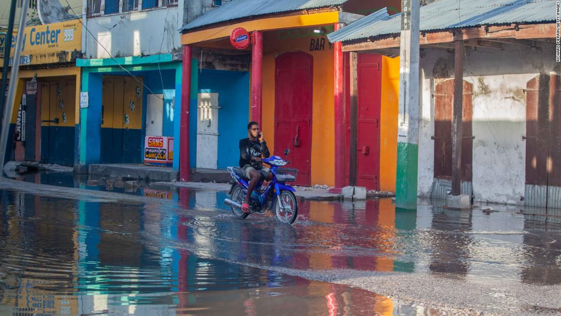 A man rides through water-logged streets.