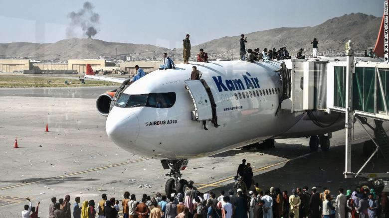 Afghan people climb atop a plane attempt to leave Kabul on Monday. The US has come under scrutiny over its hasty and chaotic withdrawal, which continued at the airport on Tuesday.