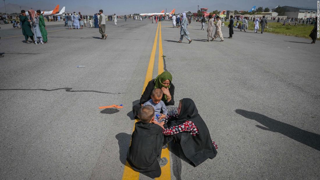 Afghans sit on the tarmac as they wait to leave the airport in Kabul on August 16.