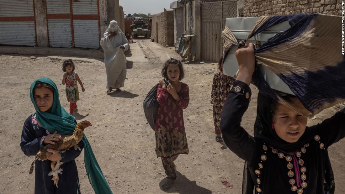 An Afghan woman and her children carry their belongings after fleeing their home in Kandahar on August 4.