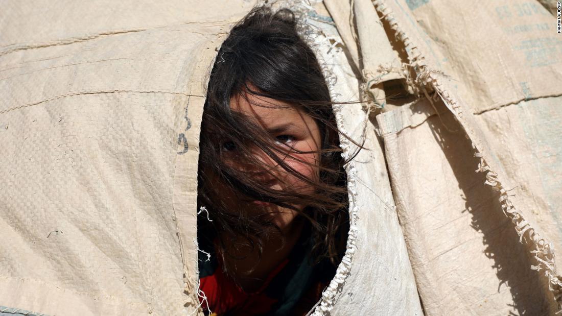 An internally displaced Afghan girl peers out of a makeshift tent at a camp on the outskirts of Mazar-i-Sharif on July 8.