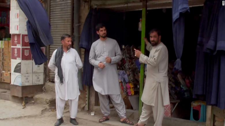 Men stand outside a clothing store in central Kabul. The store&#39;s owner told CNN he has been selling many more burqas in recent days.