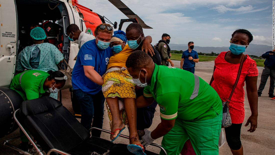 Members of the US Coast Guard assist an earthquake victim who had just arrived at the international airport in Port-au-Prince, Haiti, on Tuesday, August 17.