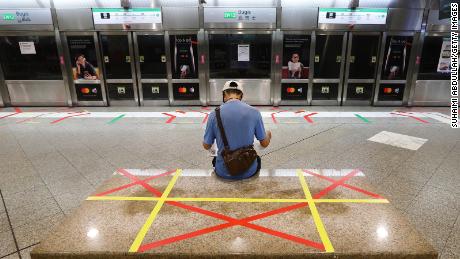 A man reading a newspaper sits on an unmarked safety distancing marker at a train station on April 21, 2020 in Singapore.