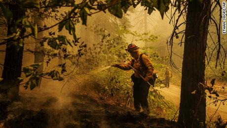 Central Calaveras firefighter Ryan Carpenter extinguishes flames from the Caldor Fire on Hazel Valley Road east of Riverton, California, on Thursday, August 19.