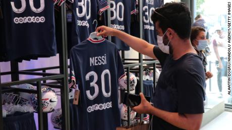 Soccer fans inspect Lionel Messi&#39;s PSG no 30 shirts during Messi&#39;s press conference announcing his signing with the club in Paris on August 11, 2021. Messi, the six time Ballon d&#39;Or trophy winner with FC Barcelona, signed a 2-year contract with an option for a third year with the French club. 