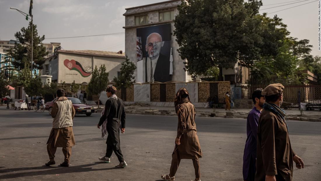 People walk past a half-destroyed poster of former Afghan President Ashraf Ghani in Kabul on August 18.