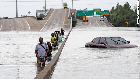 Evacuees wade down a submerged section of Interstate 610 in Houston after Hurricane Harvey in 2017 caused widespread flooding.