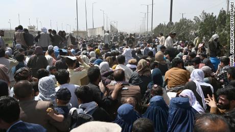 Des Afghans se rassemblent au bord d'une route près de l'aéroport de Kaboul le 20 août 2021, dans l'espoir de fuir le pays après la prise de contrôle de l'Afghanistan par les talibans.