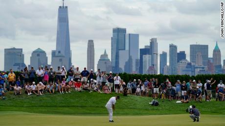 Jon Rahm, of Spain, putts on the 18th green as the Manhattan skyline looms in the distance.