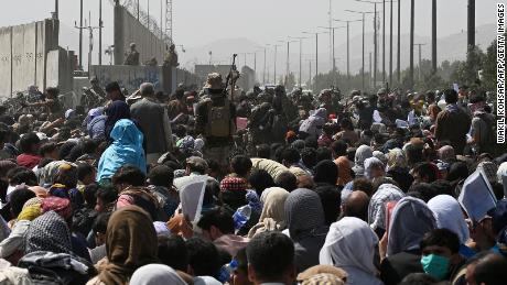 TOPSHOT - Afghans gather on a roadside near the military part of the airport in Kabul on August 20, 2021, hoping to flee from the country after the Taliban&#39;s military takeover of Afghanistan.