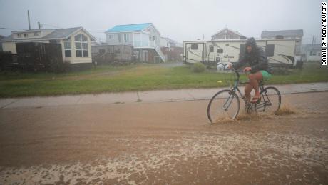 A bicyclist rides through a flooded street as Tropical Storm Henri approaches South Kingstown, Rhode Island, on Sunday, August 22.