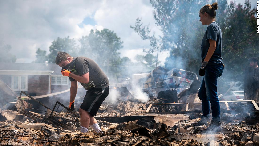 Josh Whitlock and Stacy Mathieson look through what is left of their home after it burned down following flooding in Waverly, Tennessee.