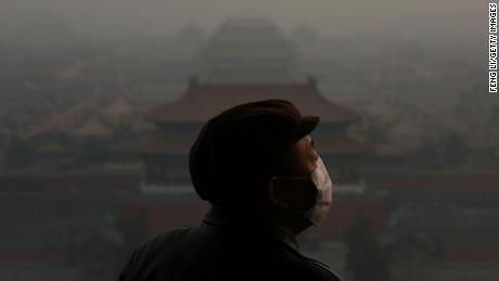 A tourist wearing a face mask looking at the Forbidden City through heavy smog in Beijing, China, on January 16, 2013.