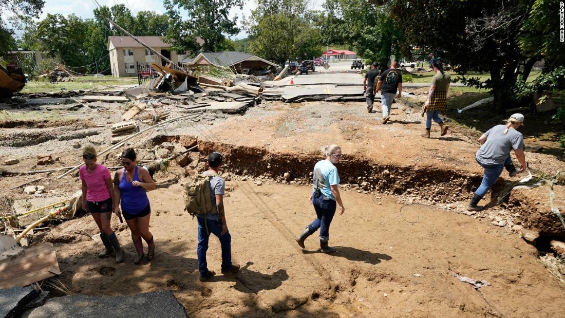 People walk across a washed-out road in Waverly, Tennessee, on Sunday, August 22.