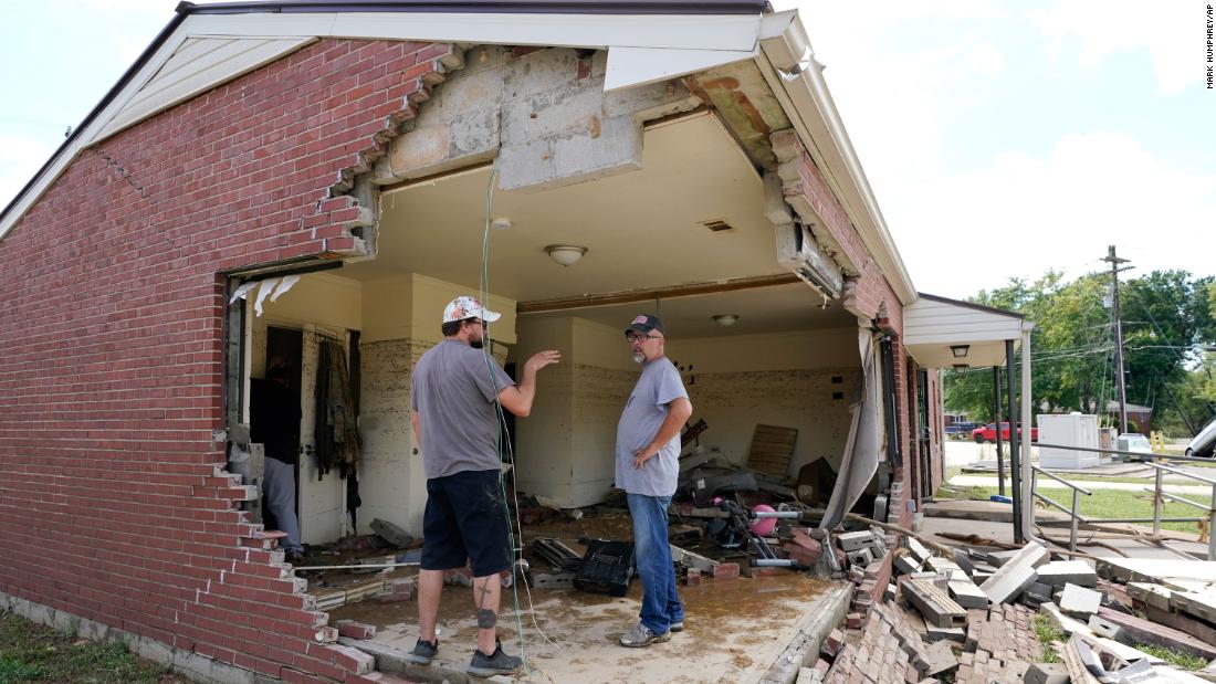 Brian Mitchell, right, looks through his mother-in-law&#39;s damaged home beside family friend Chris Hoover, left, on Sunday, August 22 in Waverly, Tennessee.