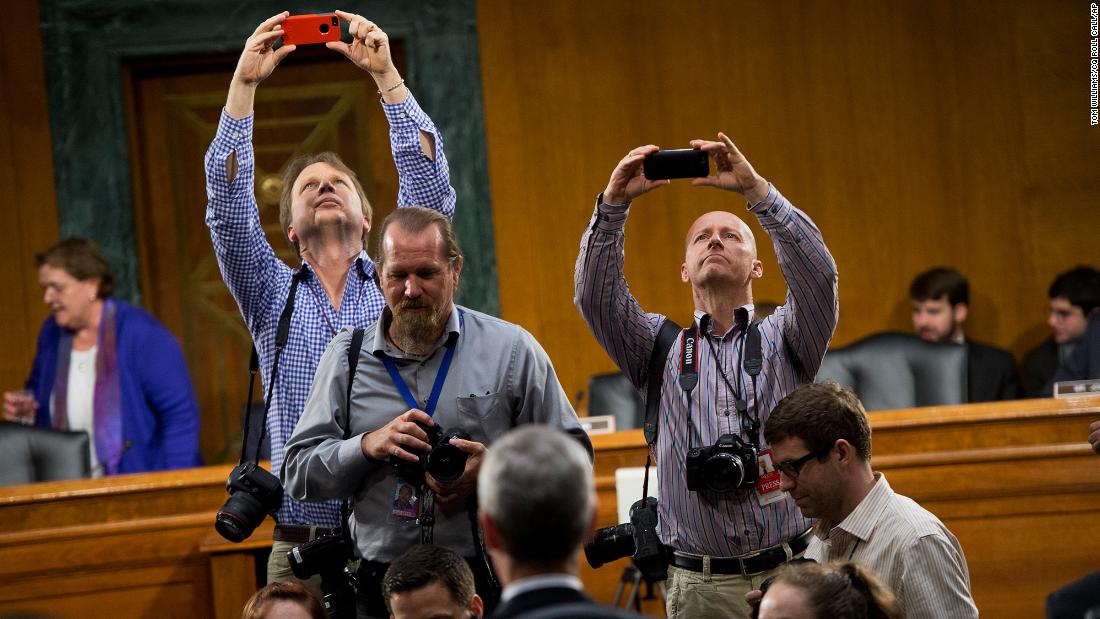 Photographers use iPhones to take photos of Cook during a break in a Senate hearing held by the Homeland Security and Governmental Affairs Subcommittee on Investigations on May 21, 2013. Cook and other Apple officials were on hand to explain the company&#39;s filings after the subcommittee accused Apple of tax avoidance.