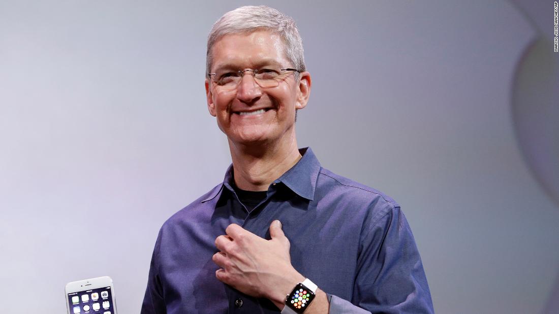 Cook, holding an iPhone 6 Plus and wearing an Apple Watch, discusses the new products during an event in Cupertino on September 9, 2014.