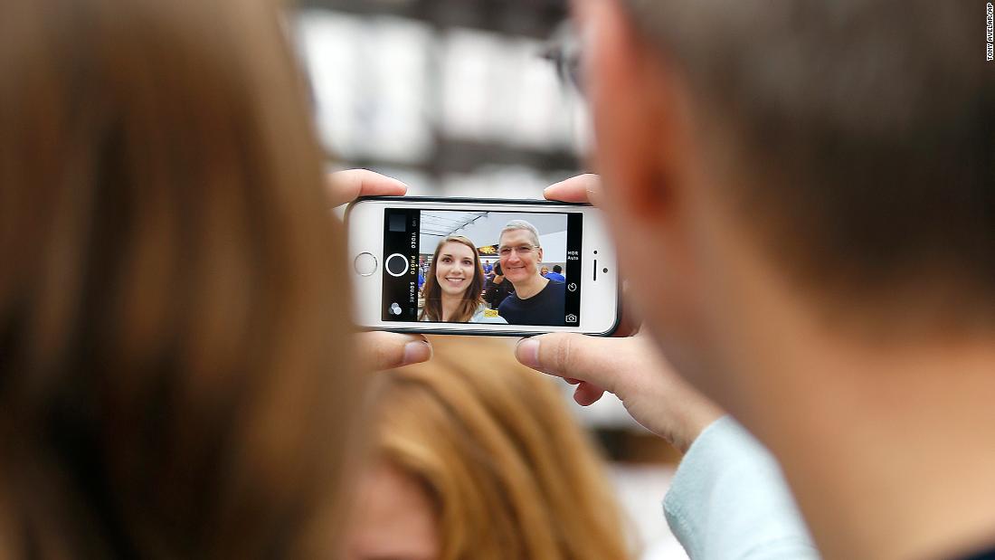 Cook, right, takes a photo with an Apple employee during the launch of the iPhone 6 at an Apple store in Palo Alto, California, on September 19, 2014.