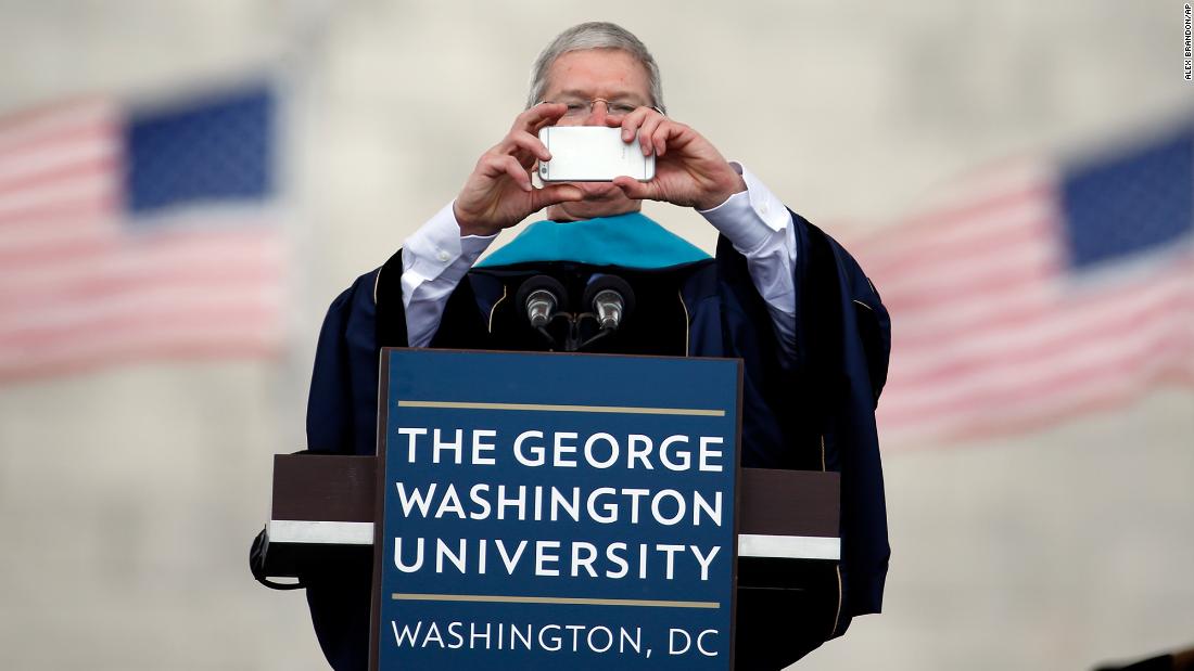 Cook takes a photo with his iPhone while addressing graduates during George Washington University&#39;s commencement exercises on the National Mall on May 17, 2015. The university awarded Cook with an honorary doctorate of public service. 