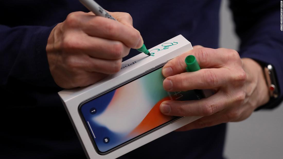Tim Cook signs the box of a new iPhone X at an Apple Store in Palo Alto on November 3, 2017. The highly anticipated iPhone X went on sale around the world that day. 