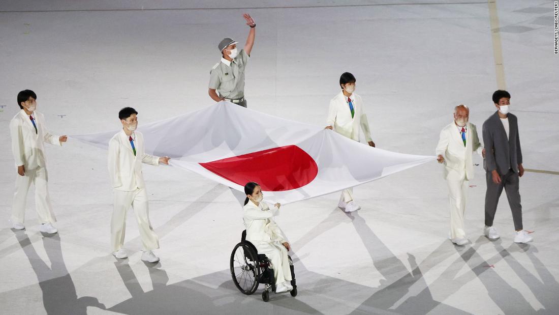Health-care workers present the Japanese flag during the opening ceremony. The Paralympics are taking place amid Japan&#39;s worst outbreak of Covid-19.