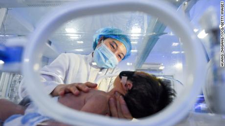 A medical worker takes care of a newborn baby lying inside an incubator on the eve of Chinese New Year on February 11 in Jingzhou, Hubei Province of China.