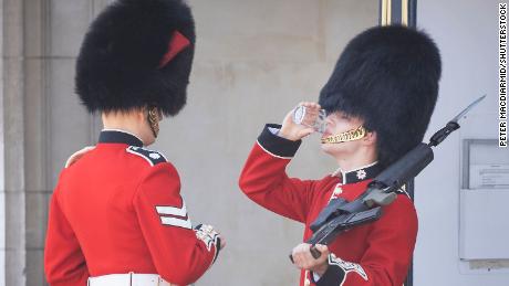 A member of the Coldstream Guards, on duty at Buckingham Palace in London, is given a drink of water during extreme heat in June 2020.