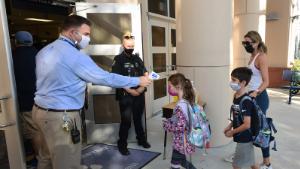 ORLANDO, FLORIDA, UNITED STATES - 2021/08/10: Principal Nathan Hay performs temperature checks on students as they arrive on the first day of classes for the 2021-22 school year at Baldwin Park Elementary School. Due to the current surge in COVID-19 cases in Florida, Orange County public schools have implemented a face mask mandate for students for 30 days unless a parent chooses to opt out of the requirement. (Photo by Paul Hennessy/SOPA Images/LightRocket via Getty Images)