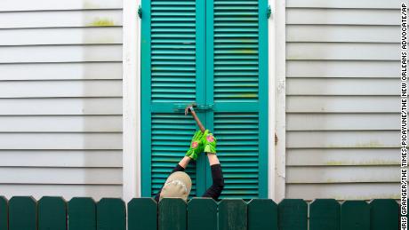 In New Orleans, a person hammers storm shutters closed as the city prepares for Ida.