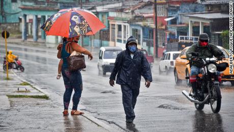 People walk under the rain in Havana on August 27, 2021, as Hurricane Ida passes through eastern Cuba.