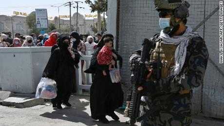 Taliban Badri fighters, a &quot;special forces&quot; unit, stand guard as Afghans walk through the main entrance gate of Kabul airport on Saturday.