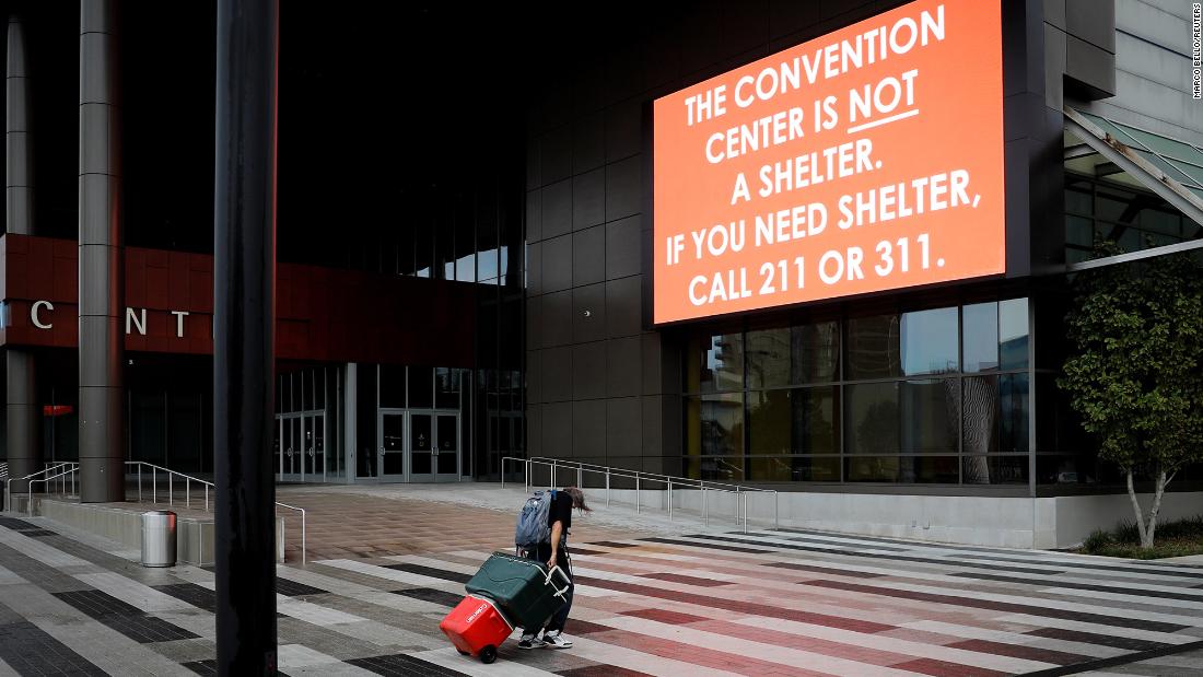 A man carrying his belongings walks past a sign outside the Ernest N. Morial Convention Center in New Orleans on Sunday.