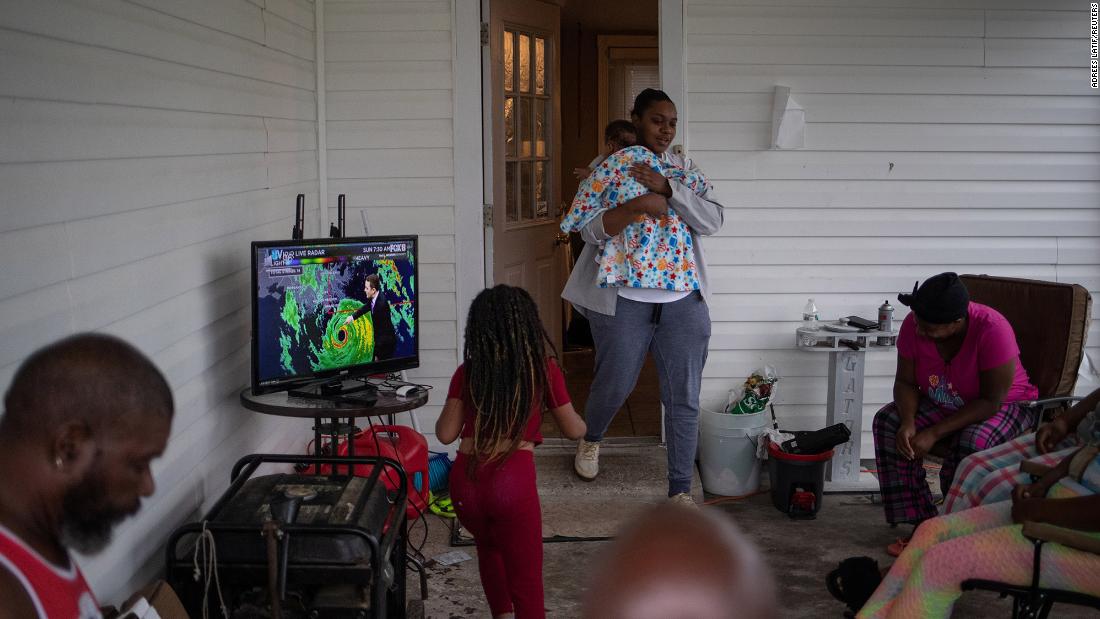LaKeisha Verdin holds her 3-month-old son, Kevin, as she walks onto the front porch where her family was watching weather updates on the local news in Houma.