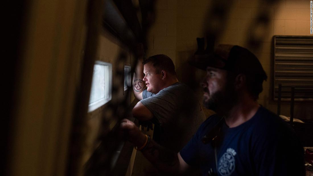 Firefighters look out the window of a shelter in Bourg on Sunday as the storm passes.