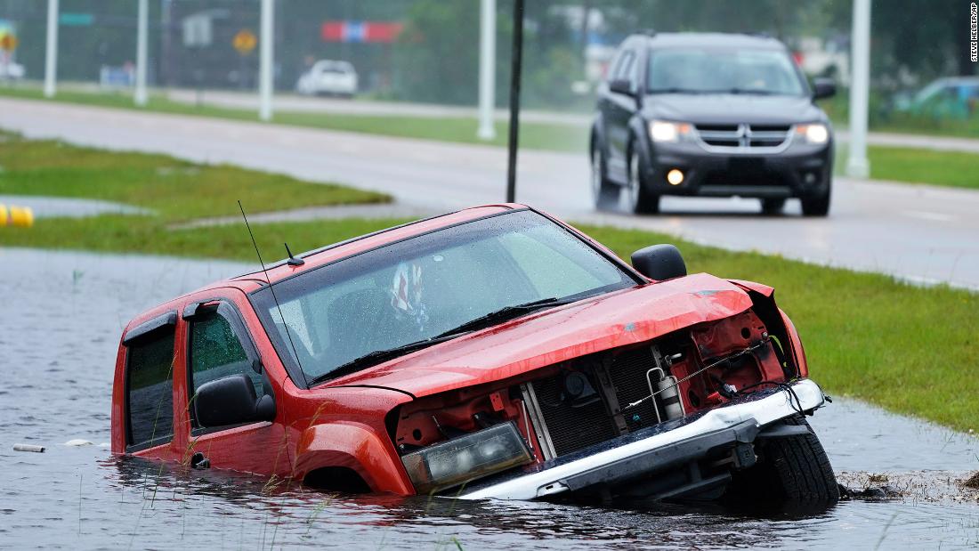 A vehicle is abandoned in a flooded ditch next to the highway Sunday in Bay Saint Louis, Mississippi.
