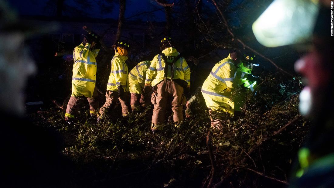Firefighters cut through downed trees on a road in Bourg on Sunday.