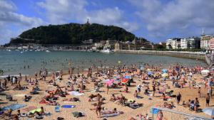 People at the Beach of the Concha in San Sebastian Guipuzkoa, Spain, on August 24, 2021. La Concha Beach is one of the best tourist areas in San Sebastián, located in the heart of the city, it offers the visitor the opportunity to enjoy magnificent views, such as the one offered by the bay in the shape of a seashell with the island of Santa Clara in the center, and on the sides the Urgull and Igeldo mountains.
