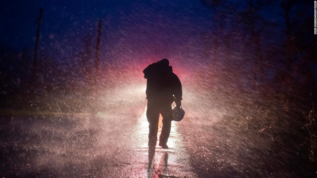 Montegut Fire Chief Toby Henry walks back to his fire truck in the rain as firefighters cut through trees on the road in Bourg, Louisiana, on Sunday, August 29.