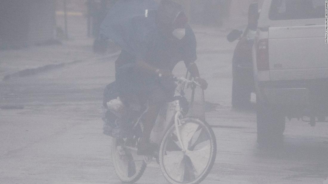 A cyclist wears a face mask while biking through the rain and high winds on Canal Street in New Orleans on Sunday.