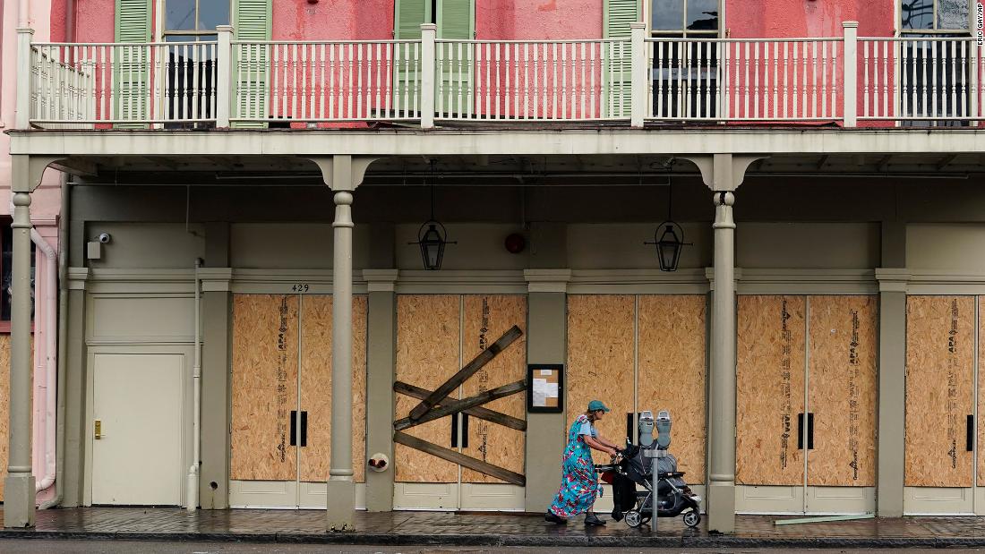 A woman pushes a stroller past a boarded up building in the French Quarter of New Orleans on Monday.