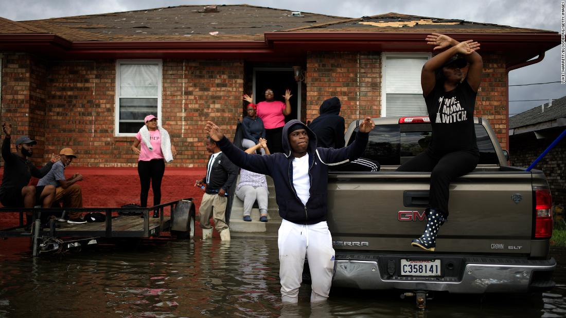 Residents wave at a US Coast Guard helicopter while waiting to be rescued from their flooded home in LaPlace on August 30.