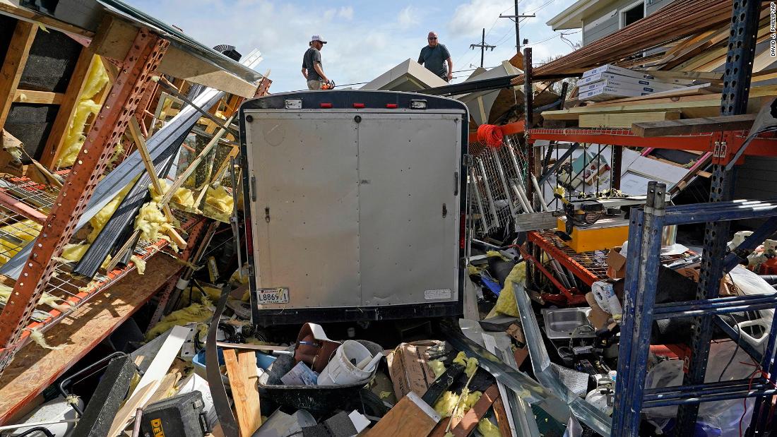 Jeremy Hodges, left, and his brother Jacob work to clear debris from their destroyed storage unit in Houma on Monday.