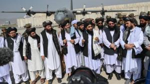 TOPSHOT - Taliban spokesman Zabihullah Mujahid (C, with shawl) speaks to the media at the airport in Kabul on August 31, 2021. - The Taliban joyously fired guns into the air and offered words of reconciliation on August 31, as they celebrated defeating the United States and returning to power after two decades of war that devastated Afghanistan. (Photo by WAKIL KOHSAR / AFP) (Photo by WAKIL KOHSAR/AFP via Getty Images)