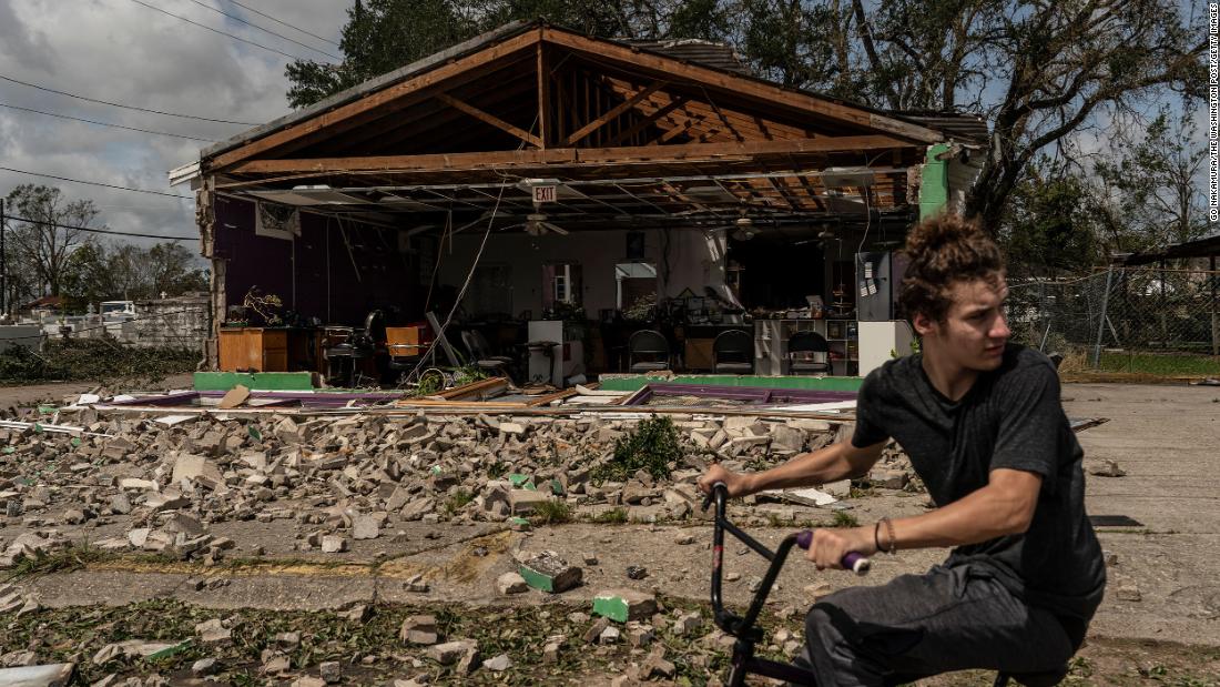 A man rides a bicycle in front of a damaged building in Houma on August 30.
