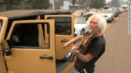 Evacuee Mel Smothers plays violin as he waits in a miles-long traffic jam on Hwy 50. 