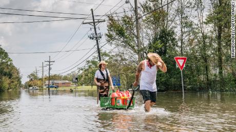 Les résidents déplacent un chariot avec des bidons d'essence dans un quartier inondé mardi à Barataria, en Louisiane. 